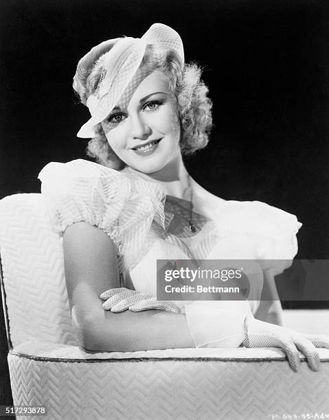 Ginger Rogers, vivacious RKO player wears a lovely bouffant evening gown of yellow striped mousseline. It is backless and features the inevitable,...