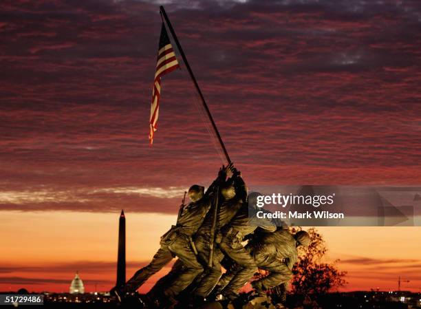 The early morning sun begins to rise behind the Iwo Jima Memorial on November 11, 2004 in Arlington, Virginia. The 17th annual Veterans Day Parade...