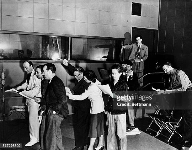Orson Welles, guiding genius of the Mercury Theatre of the Air is shown {hands upraised} in action here at a microphone as he directed a rehearsal of...