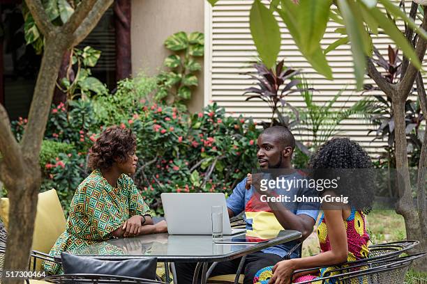 nigerianische kollegen mit laptop reden im garten - lagos stock-fotos und bilder