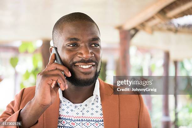 young african man on cell phone, looking away smiling - nigeria man stock pictures, royalty-free photos & images