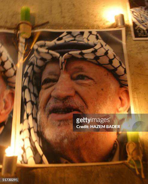 Candles are lit under portraits of late Palestinian leader Yasser Arafat, outside the Muqataa, Arafat's West Bank headquarters in the city of...