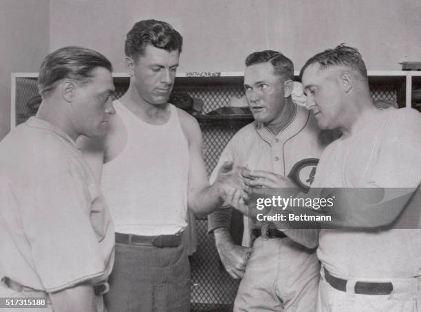 Charlie Grimm, Captain and first sacker of the Pennant bound cubs, displaying his injured hand to teammates is shown. Left to right are Hack Wilson,...