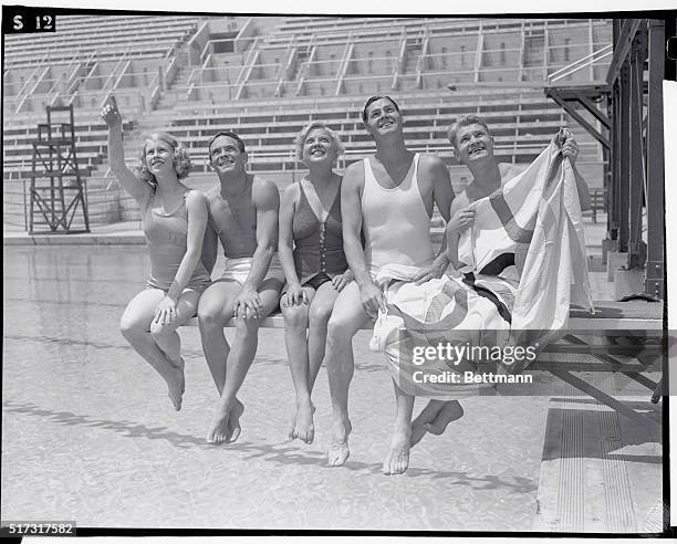 Marjorie Gestring, Dutch Smith, Georgia Coleman, Johnny Weissmuller and Mickey Riley holding the Olympic flag, sit together on a diving board, Los...