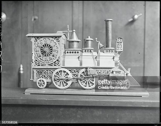 Clock in form of engine, all of wood, valued at $25,000. Boston, Mass. George Kropelman, Boston jeweler is shown with the model which he owns, of a...
