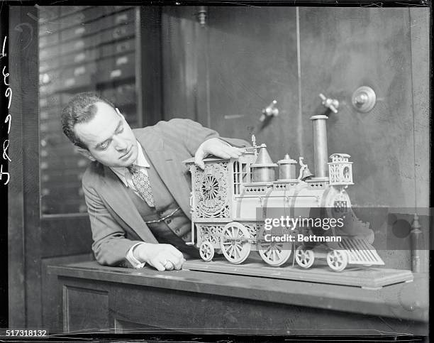 Clock in form of engine, all of wood, valued at $25,000. Boston, Mass. George Kropelman, Boston jeweler is shown with the model which he owns, of a...