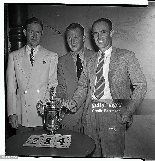 Byron Nelson, Craig Wood, and Denny Shute , as each man has a hand on the trophy, after they shot themselves into a three-way tie for the National...