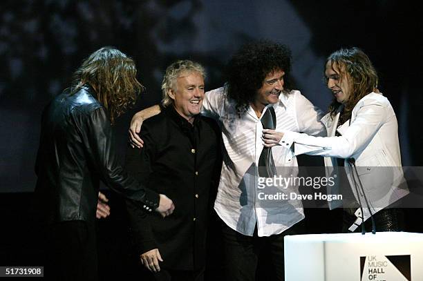 The Darkness members Dan and Justin Hawkins present Queen members Roger Taylor and Brian May with the award for 'Induction for 1970's' at the final...