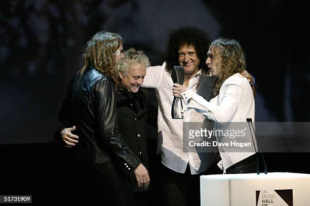 The Darkness members Dan and Justin Hawkins present Queen members Roger Taylor and Brian May with the award for 'Induction for 1970's' at the final...