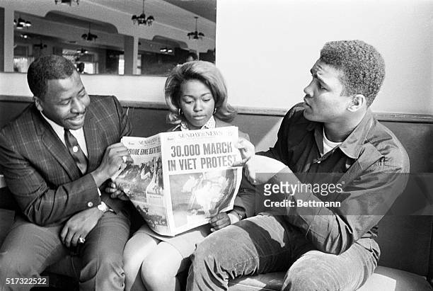 Cassius Clay points to newspaper headline to show he's not the only one protesting the Vietnam War, March 28th. The heavyweight champ was relaxing...