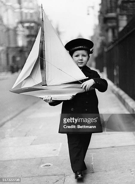 Four-year-old Tommy Sopwith wears proper naval attire to play with his model of the Endeavor, a British yacht that vied for the America's Cup in 1934.