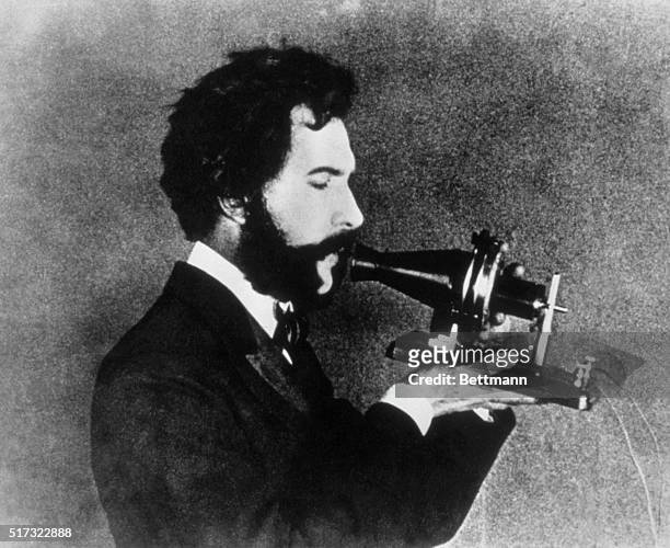An actor portraying Alexander Graham Bell speaking into the Centennial telephone.