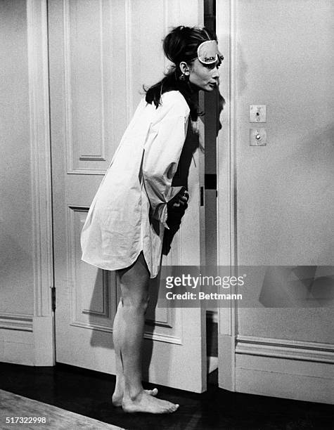 Anything but prosaic in terms of costume, screen star Audrey Hepburn listens mischievously at the door in a scene from her latest movie. Barefoot and...