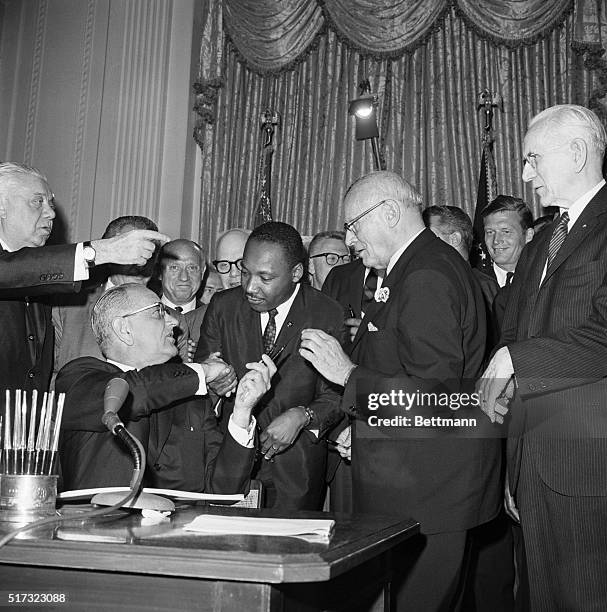 President Johnson shakes hands with civil rights leader Martin Luther King, Jr., and hands him a pen to sign the Civil Right Act on July 2, 1964.