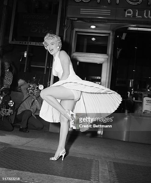 Film star Marilyn Monroe poses over a Manhattan subway grate as the wind blows her white dress up. Photographers capture the moment on camera, which...