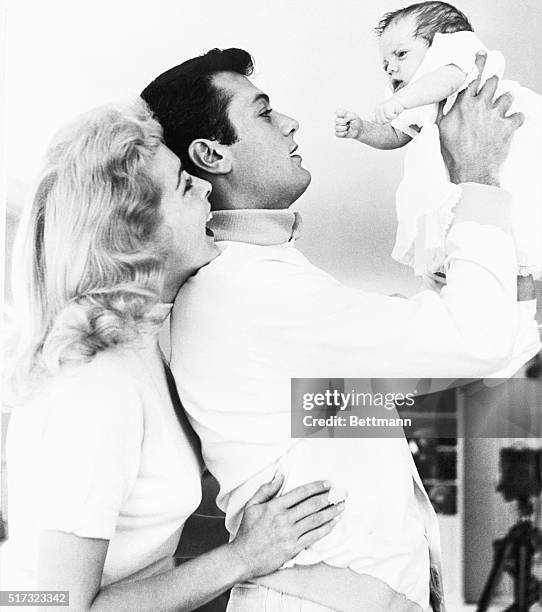 Actor Tony Curtis holds his eight-week-old daughter Kelly Lee Curtis. His wife, and Kelly Lee's mother, actress Janet Leigh, looks on happily.