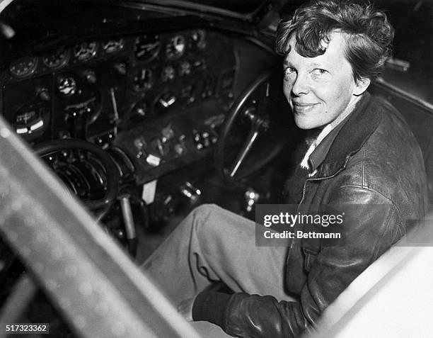 Amelia Earhart smiles as she sits clad in a leather aviator's jacket in the cockpit of a small airplane. One of the world's most famous aviators,...