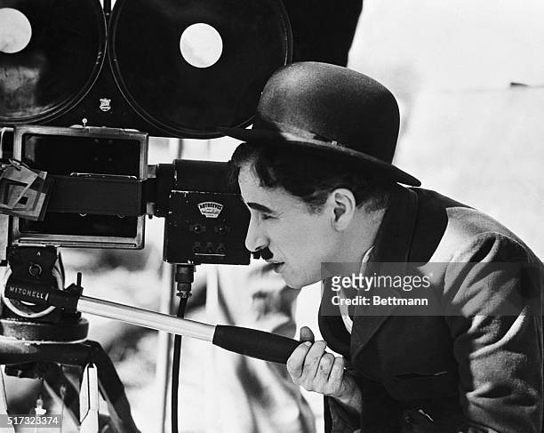Actor Charlie Chaplin looks though a movie camera on April 22, 1935. He is directing, as well as acting in, a comedy tentatively titled Production...