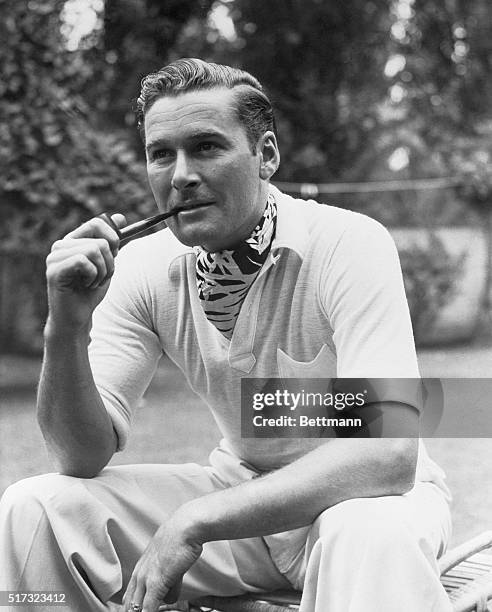 Errol Flynn seated smoking pipe. Undated Photo.