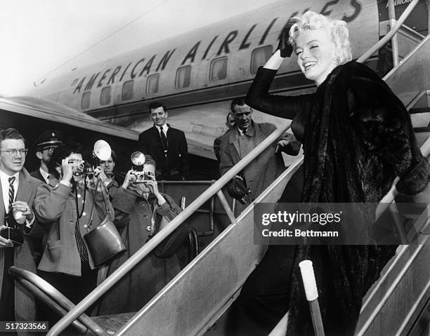 New York, NY: In perfect form as usual Marilyn Monroe obliges Lens Corps at Idlewild as she boards an American Airlines plane for Hollywood.