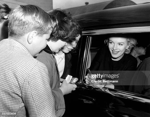 New York, NY: Marilyn Monroe signing autographs for children upon her arrival at Idlewild Airport from the coast. Photograph 6-2-1956, shortly after...
