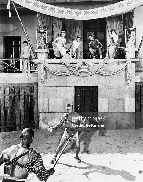 Spartacus battles with Draba as his wife Varinia , watches in the balcony with members of the Roman royalty : Helena Glabrus , Marcus Licinius...