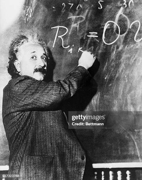 Theoretical physicist Albert Einstein writes a complicated equation on a blackboard. He is at the California Institute of Technology for a lecture...