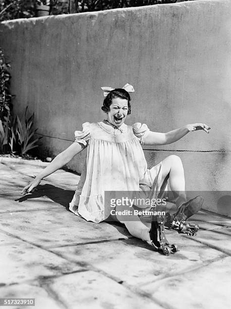 Fanny Brice, portraying the character Baby Snooks, sits on the sidewalk after falling on her roller skates.