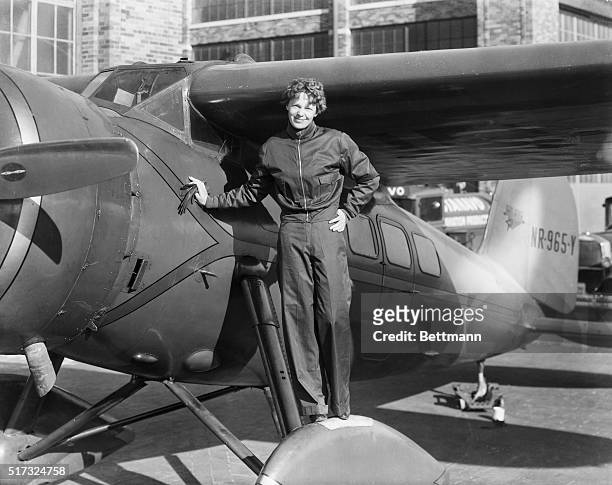 Amelia Earhart , American aviatrix, first woman to cross Atlantic. Photograph showing her with airplane.