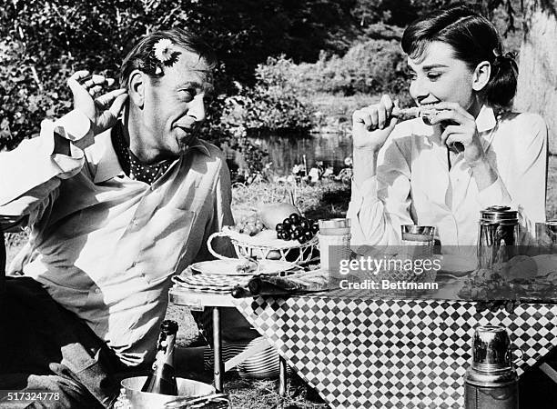 Paris, France: Gary Cooper, playing the role of a philandering American, is shown wooing Audrey Hepburn at a De Luxe picnic for two in their new...