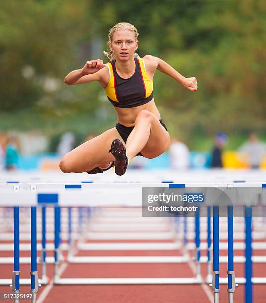 vorderansicht des beuatiful junge frauen rennen 100-meter-hürdenlauf - hurdle stock-fotos und bilder