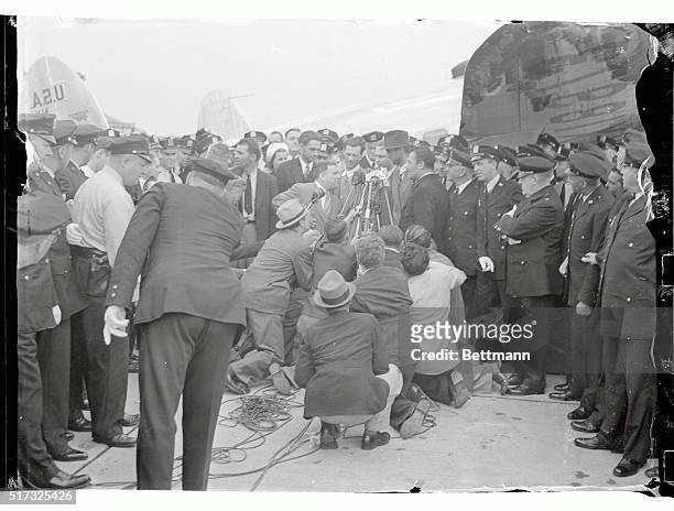 Howard Hughes and his flying companions as they were greeted by officials shortly after bringing their plane down at the airport here, concluding...