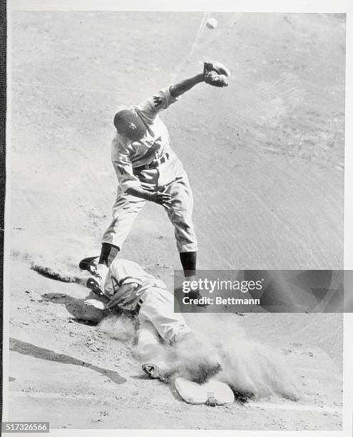 Wally Moses, right fielder for the Philadelphia Athletics, slides safely into third on Newsome's infield hit as first sacker Kuhel throws over...