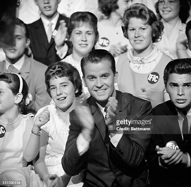 Dick Clark is seated in the audience during the filming of an episode of "American Bandstand".