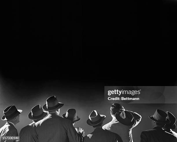 Group of behatted men looking into the night.