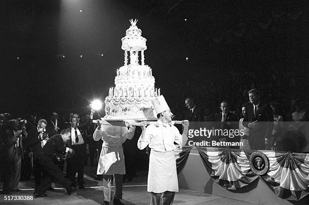 Two chefs carry a multi-tiered birthday cake for President John F. Kennedy, who watches from the side, on May 20, 1962. The celebration took place at...