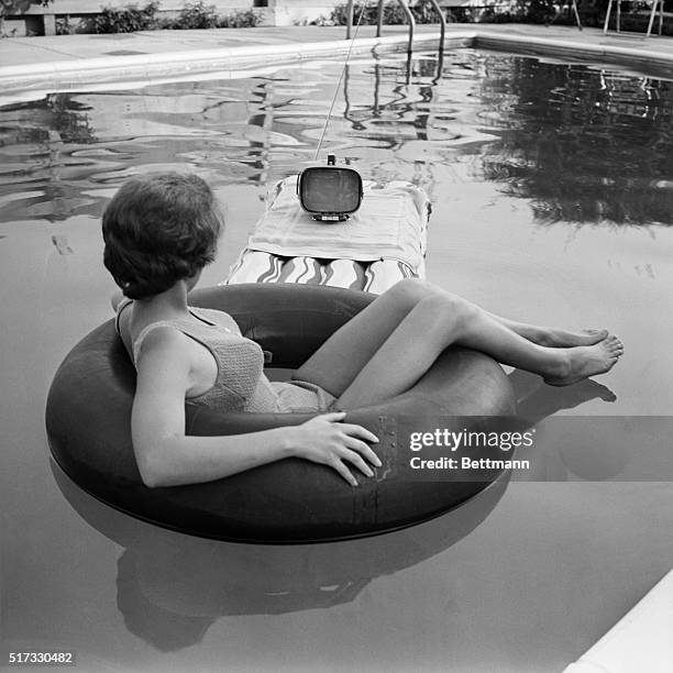 Nineteen year old Joyce McGee relaxes in front of the television while cooling off in the swimming pool. The portable Sony television uses...