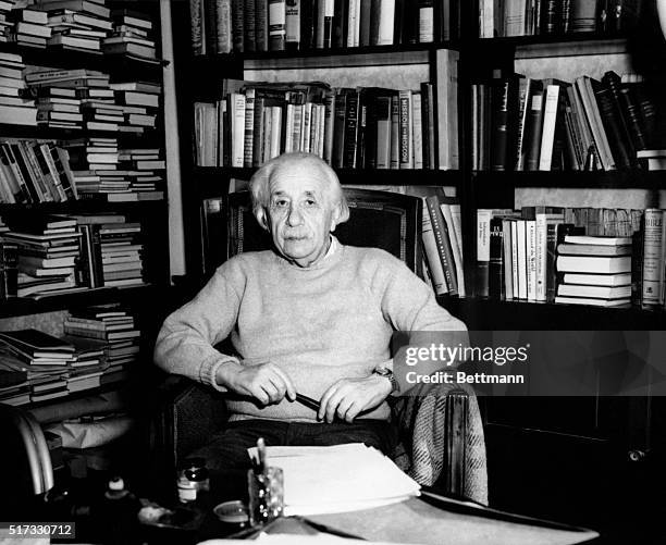 Albert Einstein famed theoretical physicist seated in front of bookcase.