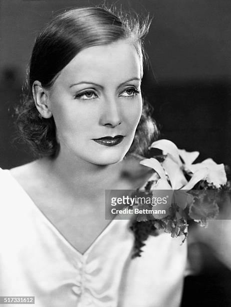 Head and shoulders portrait of Greta Garbo wearing an orchid.