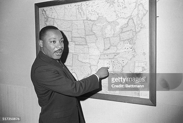 Atlanta, GA: Dr. Martin Luther King points to Selma, Alabama on a map at a Southern Christian Leadership Conference office, as he calls for a...