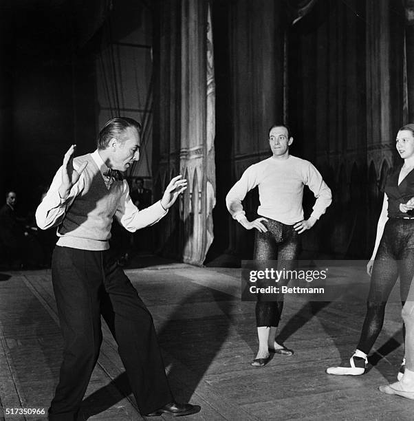 George Balanchine, noted choreogtapher, demonstrates a movement for John Field and Berly Grey. Undated photograph.