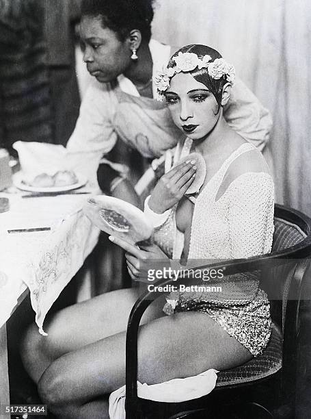 Vienna, Austria - Josephine Baker getting ready in her dressing room. She is depicted putting on makeup looking into a mirror. BPAII