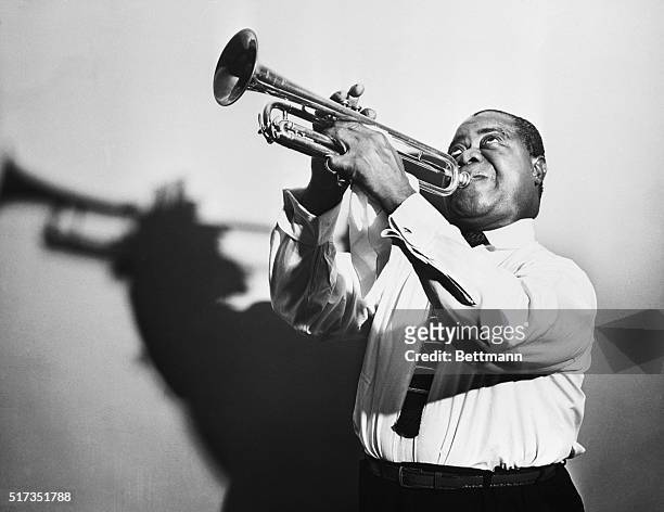 Louis Armstrong blows a horn in a publicity picture.