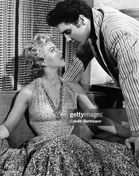 Elvis Presley and actress Ann Neylan in a scene from the Avon Production, "Jailhouse Rock." She is seated in a loveseat as the rock and roll star...