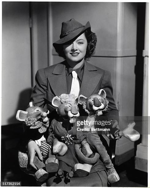 Myrna Loy, 1905-1993, American film actress. She poses for the photograph wearing a man's jacket, hat and tie. She holds three stuffed lions, dressed...