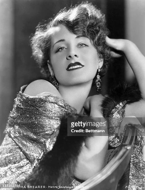 Glamour-style publicity photograph of the Metro-Goldwyn-Mayer actress, Norma Shearer. She is shown in glittering, clothing and jewellry,...