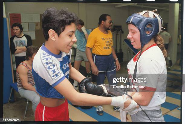After her sparring match, fellow boxer Ernie Calanchi removes gloves from Jill Lafler, the young girl who wants to fight the Golden Gloves boxing...