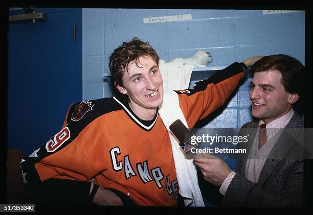 Wayne Gretzky, #99 of the Edmonton Oilers, is shown talking to a reporter in the locker room after his fabulous four-goal performance in the NHL...