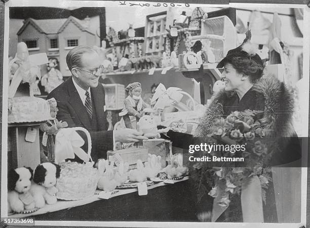 Joseph P. Kennedy, United States Ambassador to Great Britain, is shown as he sold the first doll to Mrs. Kennedy after he had officially opened the...
