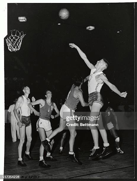 Big G.N. Munro of Canada gets off a one-handed shot despite the defensive tactics of G.Bersani of Italy during Olympic basketball game at Harringay...